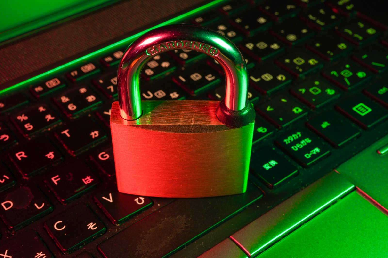 A red padlock resting on a backlit Japanese-layout computer keyboard