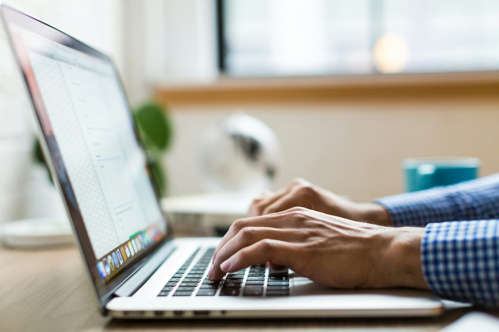 A person typing on a laptop keyboard, working at a desk