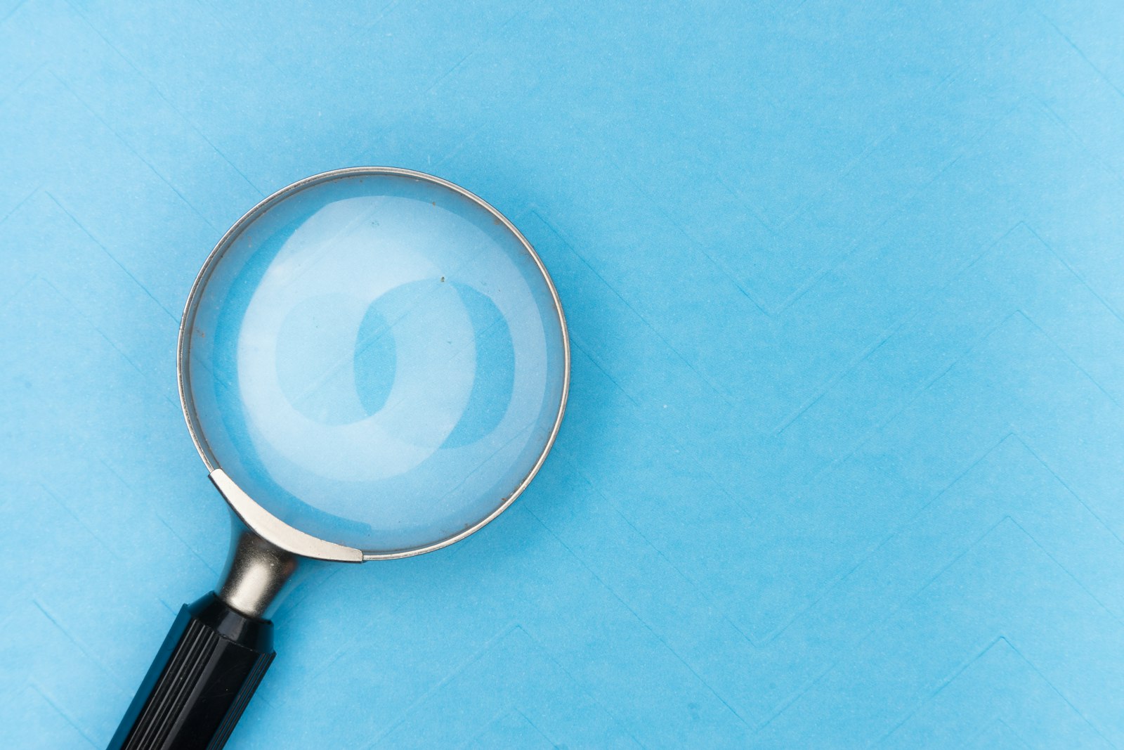 A magnifying glass resting on a plain blue background